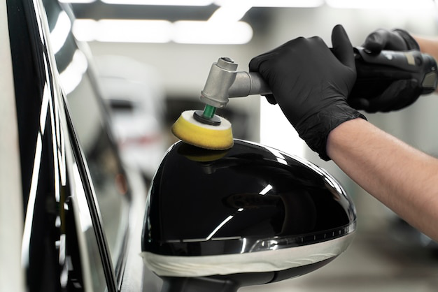 A car detailer polishing a car’s rearview mirror
