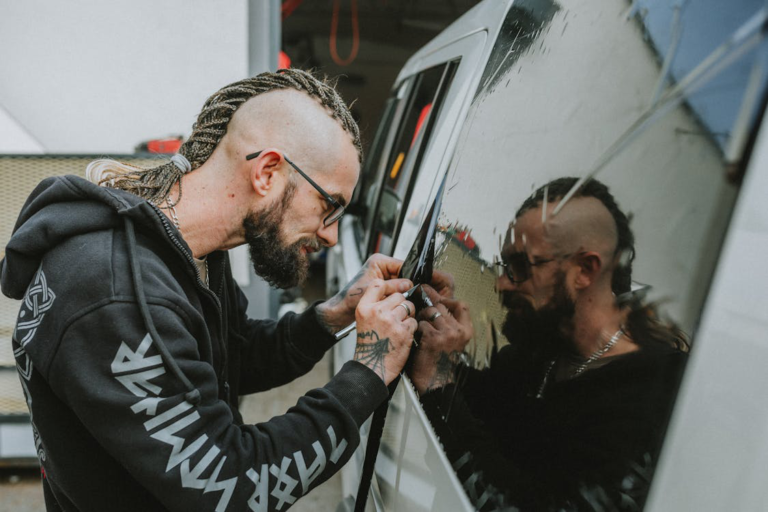 A professional installing a dark window tint on a car window